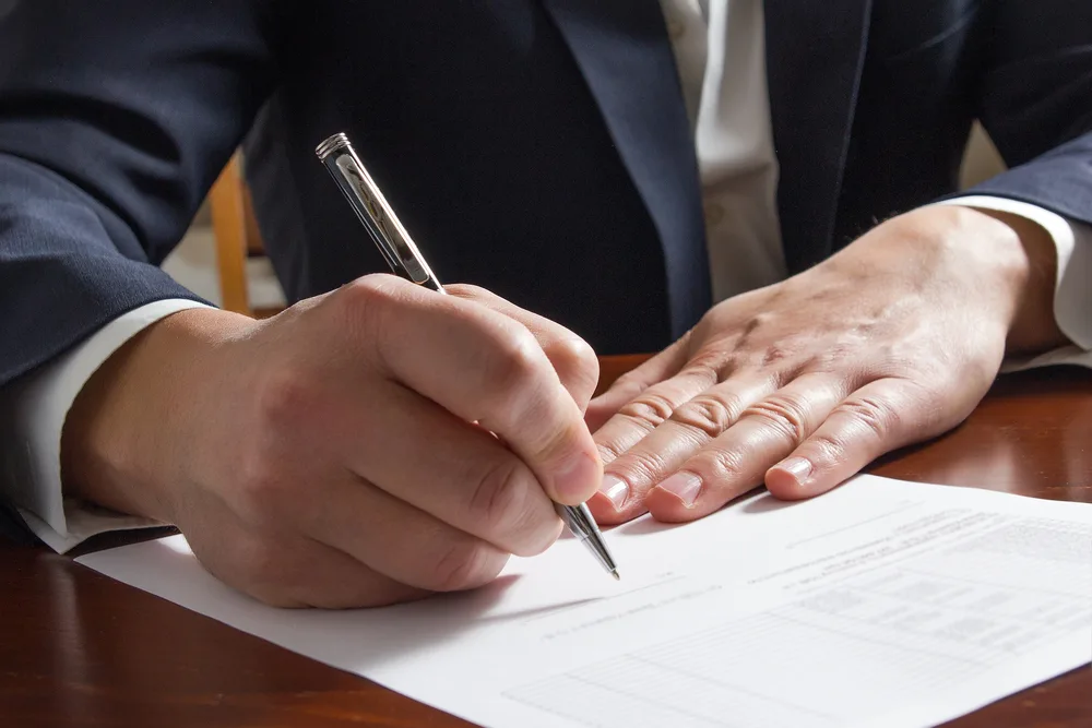 No Fee Guarantee, Photo of a man writing an paper at the table