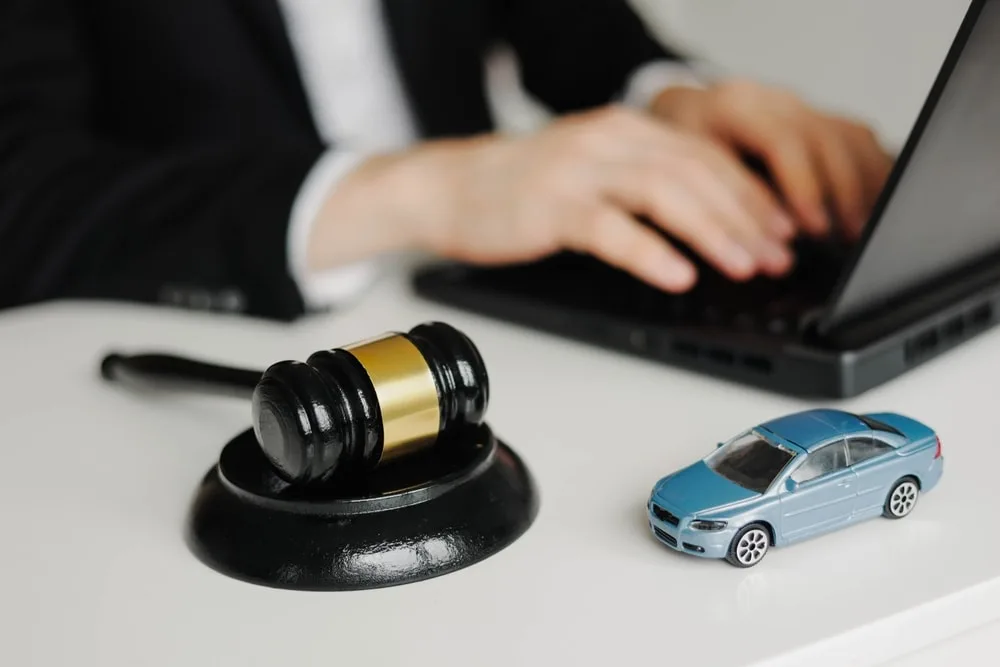 Car accident attorney working on a laptop beside a gavel and a small toy car