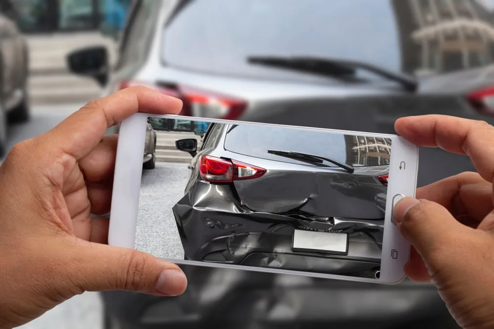 Person taking a photo of damaged car