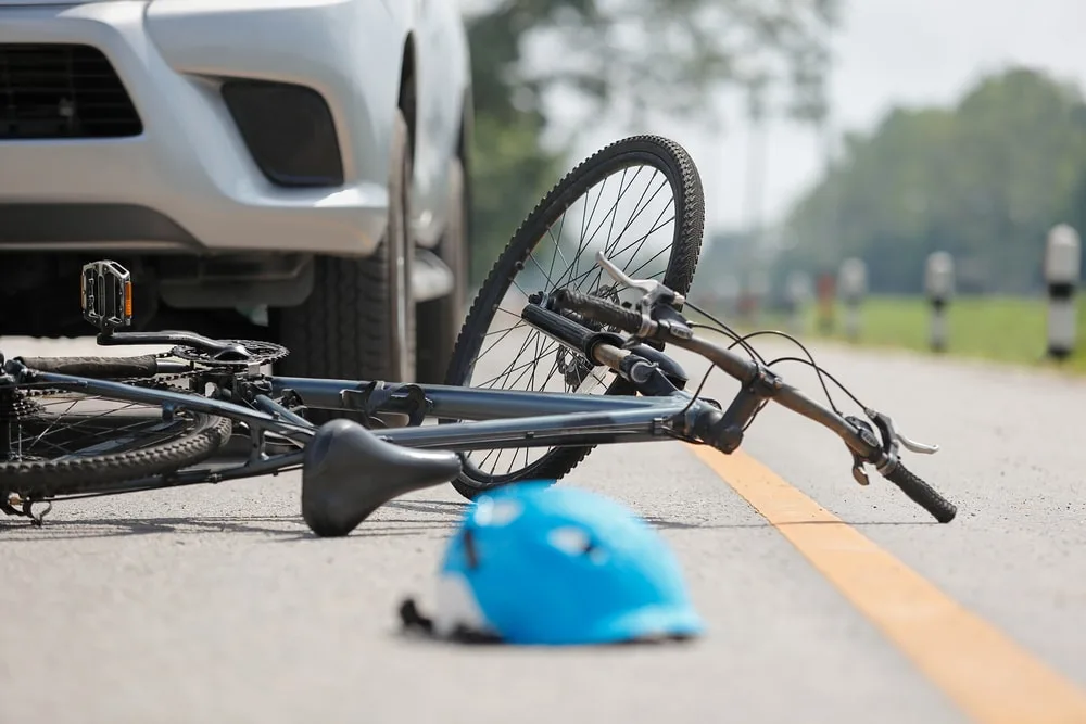 Closeup of a damaged bicycle and helmet by a car after an accident